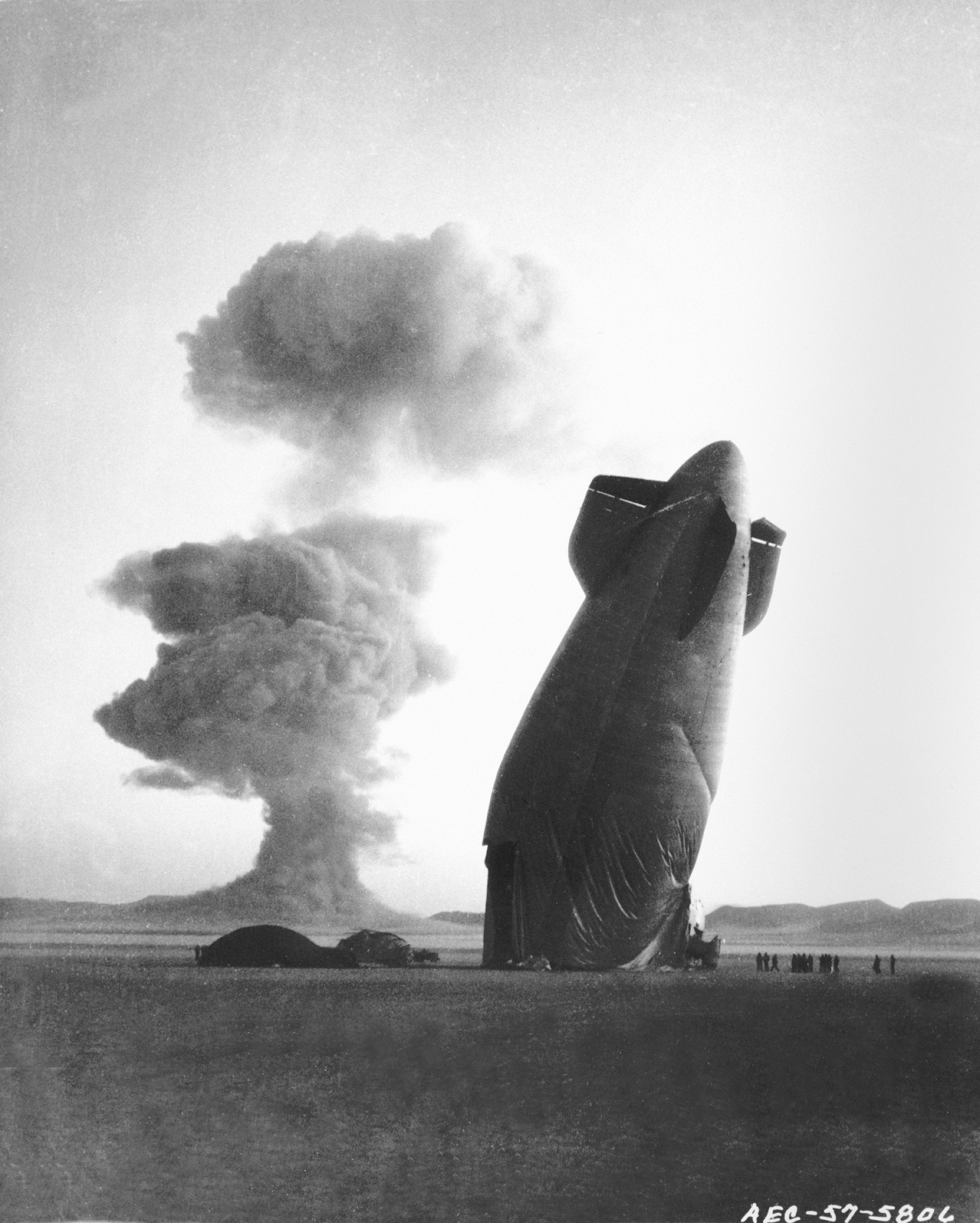 PLUMBBOB/STOKES/dirigible – Nevada test Site, August 7, 1957. The tail, or “After” section of a U.S. Navy Goodyear ZSG-3 Blimp is shown with the Stokes cloud in background. The dirigible was in